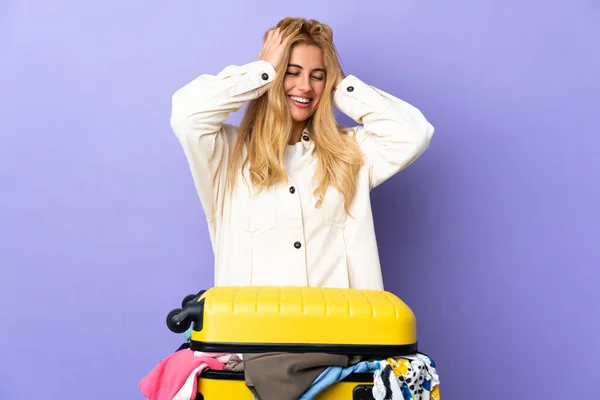 Młoda Urugwajska Blondynka Walizką Pełną Ubrań Odizolowanej Fioletowej Ścianie Śmiejąca — Zdjęcie stockowe