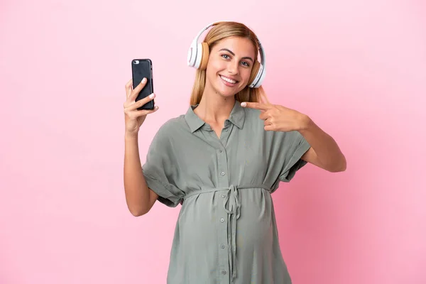 Молодая Уругвайская Женщина Изолирована Синем Фоне Беременной Слушает Музыку Мобильного — стоковое фото