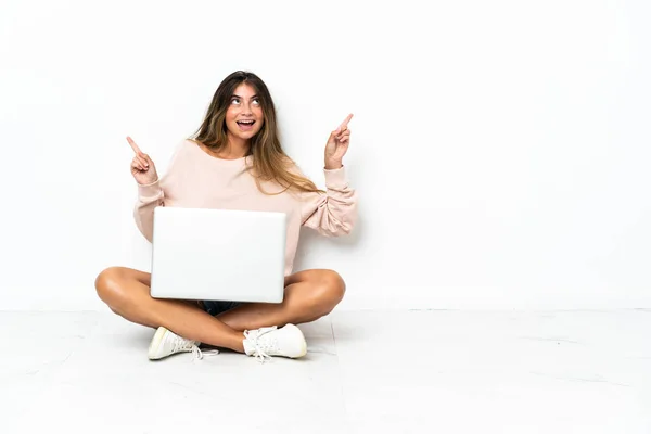 Młoda Kobieta Laptopem Siedząca Podłodze Odizolowana Białym Tle Wskazując Palcem — Zdjęcie stockowe