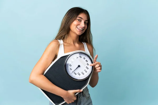 Young Caucasian Woman Isolated Blue Background Holding Weighing Machine Pointing — Stock Photo, Image