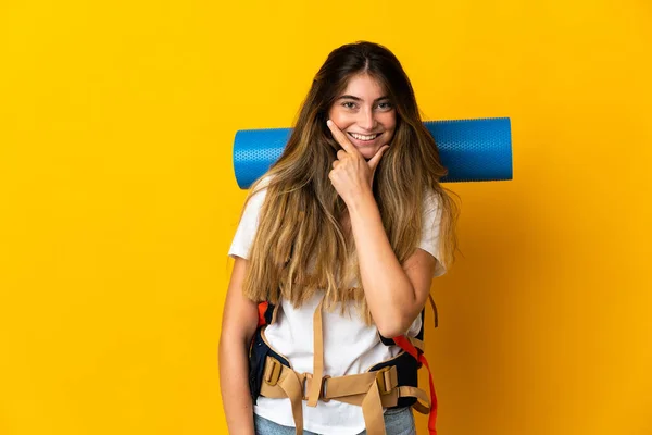 若い登山家の女性は大きなバックパックを黄色の背景に幸せと笑顔に隔離された — ストック写真