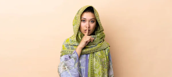 口に指を入れて沈黙のジェスチャーの兆候を示すベージュの背景に隔離されたインドの女性 — ストック写真