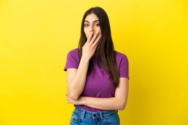 Sarı arka planda izole edilmiş genç beyaz kadın sağa bakarken şaşırdı ve şok oldu.