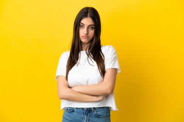 Sarı arka planda izole edilmiş genç beyaz kadın üzgün hissediyor.