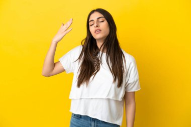 Sarı arka planda izole edilmiş, yorgun ve hasta bir ifadeyle genç beyaz bir kadın.