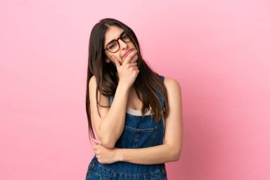 Pembe arka planda izole edilmiş beyaz bir kadın. Şüpheleri var.