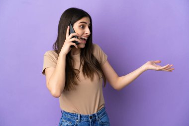 Mor arka planda izole edilmiş cep telefonu kullanan beyaz bir kadın.