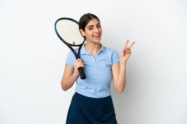 Yakışıklı genç tenisçi beyaz arka planda izole edilmiş beyaz kadın gülümsüyor ve zafer işareti gösteriyor.