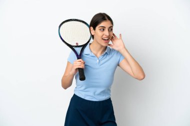 Yakışıklı genç tenisçi, beyaz arka planda izole edilmiş beyaz bir kadın. Kulağına elini sürerek bir şeyler dinliyor.