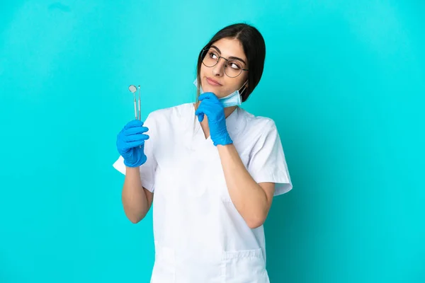 Junge Kaukasische Zahnärztin Frau Hält Werkzeuge Isoliert Auf Blauem Hintergrund — Stockfoto
