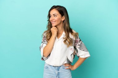 Soyutlanmış mavi arka planda genç bir kadın yana bakıyor ve gülümsüyor.