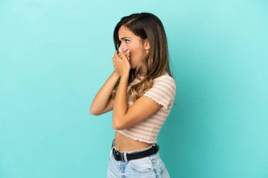 Ağız kapsayan izole mavi arka plan üzerinde genç kadın ve yan bakıyor