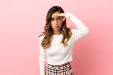 Izole arka plan üzerinde genç kadın uzak el ile bir şey bakmak için bakıyor