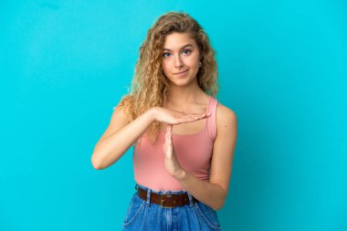 Mavi arka planda izole edilmiş genç sarışın bir kadın.