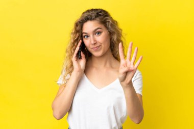 Sarı arka planda izole edilmiş cep telefonu kullanan genç sarışın kadın mutlu ve parmakları olan dört kişi sayıyor.
