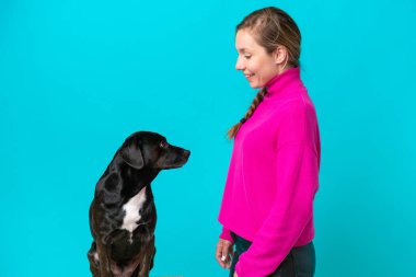 Köpeği olan beyaz bir kadın mavi arka planda mutlu bir ifadeyle izole edilmiş.