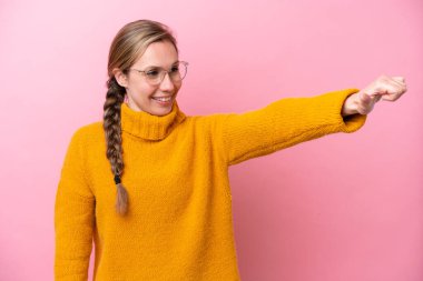 Pembe arka planda izole edilmiş beyaz bir kadın baş parmak hareketi yapıyor.