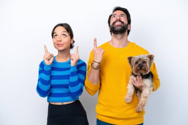 Beyaz arka planda izole edilmiş bir köpeği tutan genç İspanyol kadın işaret parmağıyla işaret etmek harika bir fikir.