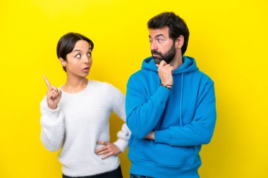 Kafkasyalı genç çift sarı arka planda izole edilmiş duruyor ve bir fikir düşünüyorlar.