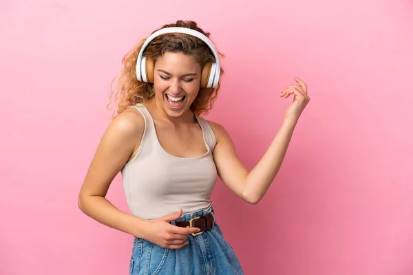 Νεαρή Ξανθιά Γυναίκα Απομονωμένη Ροζ Φόντο Ακούγοντας Μουσική Και Κάνοντας — Φωτογραφία Αρχείου