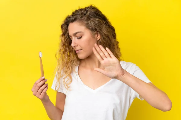 Νεαρή Καυκάσια Γυναίκα Κρατώντας Ένα Βούρτσισμα Των Δοντιών Απομονώνονται Κίτρινο — Φωτογραφία Αρχείου