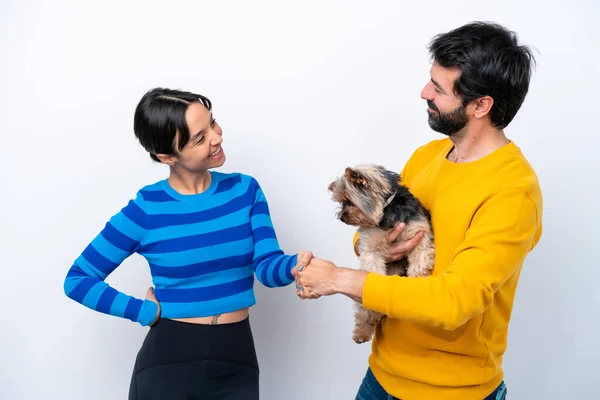 Young hispanic woman holding a dog isolated on white background handshaking after good deal