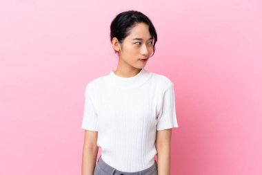 Genç Vietnamlı kadın pembe arka planda izole edilmiş.