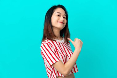 Genç Vietnamlı kadın mavi arka planda yalnız gururlu ve kendini beğenmiş.