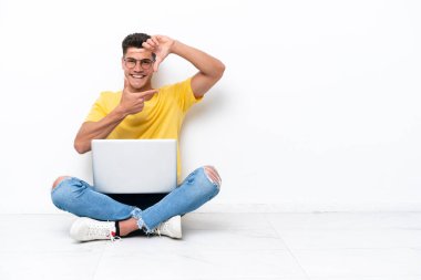 Yerde oturan genç adam, beyaz arka planda izole edilmiş, odaklanmış bir yüz. Çerçeve sembolü