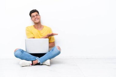 Genç adam beyaz arka planda izole bir şekilde yerde oturuyor. Bir fikir sunuyor.