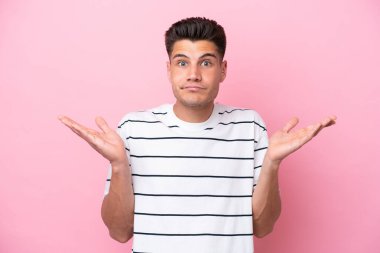 Pembe arka planda izole edilmiş genç beyaz adam şüpheli hareketler yapıyor.