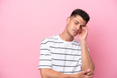 Kafkasyalı genç adam pembe arka planda izole edilmiş, baş ağrısı var.