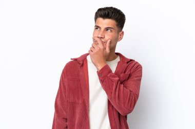 Beyaz arka planda izole edilmiş genç beyaz bir adam. Şüpheleri var ve kafası karışmış bir yüz ifadesi var.