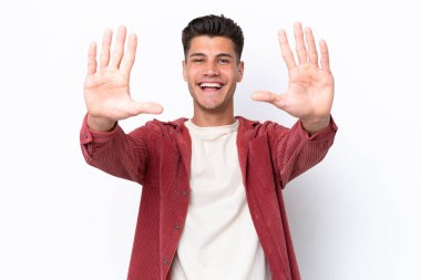 Beyaz arka planda izole edilmiş beyaz tenli genç adam parmaklarıyla ona kadar sayıyor.