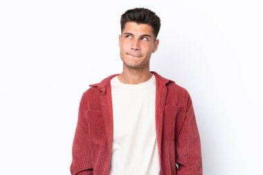 Beyaz arka planda izole edilmiş genç beyaz adam yukarı bakarken şüpheleri var.