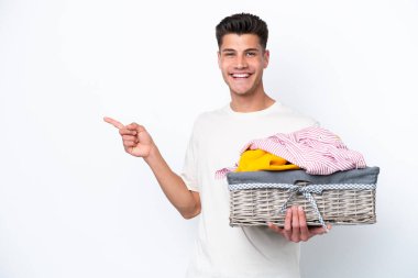Çamaşır sepetini tutan genç beyaz arka planda izole edilmiş beyaz bir adam.