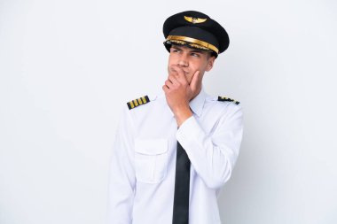 Kafkasyalı uçak pilotu beyaz arka planda izole edilmiş, kuşkuları var ve kafası karışmış bir yüz ifadesi var.