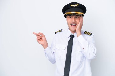 Beyaz arka planda izole edilmiş Kafkasyalı uçak pilotu şaşırdı ve parmağını yana çevirdi.