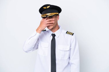 Kafkasyalı uçak pilotu beyaz arka planda izole edildi. Gözlerini elleriyle kapadı ve gülümsedi.