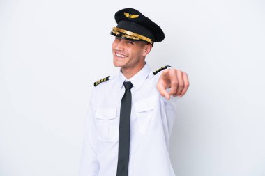 Beyaz arka planda izole edilmiş Kafkasyalı uçak pilotu kendine güvenen bir ifadeyle parmağını sana gösteriyor.