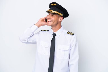 Beyaz arka planda izole edilmiş Kafkasyalı uçak pilotu cep telefonuyla sohbet ediyor.