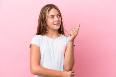 Pembe arka planda izole edilmiş küçük beyaz kız harika bir fikre işaret ediyor.