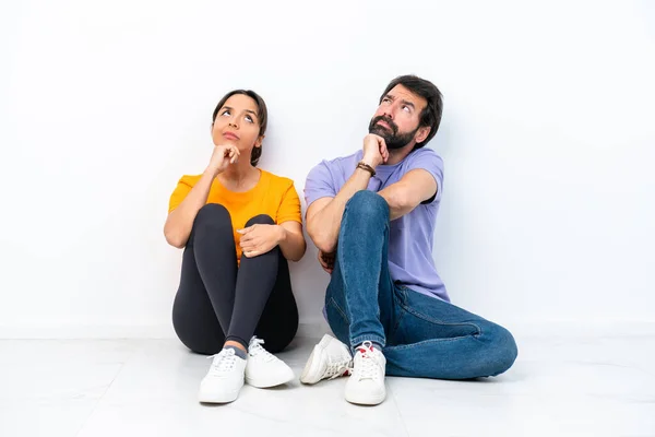 Young Caucasian Couple Sitting Floor Isolated White Background Standing Thinking — 图库照片
