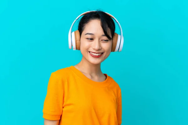 Mujer Vietnamita Joven Aislada Sobre Fondo Azul Escuchando Música — Foto de Stock