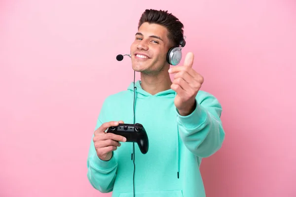 Νεαρός Όμορφος Καυκάσιος Άνδρας Παίζει Ένα Χειριστήριο Βιντεοπαιχνιδιών Απομονωμένο Ροζ — Φωτογραφία Αρχείου