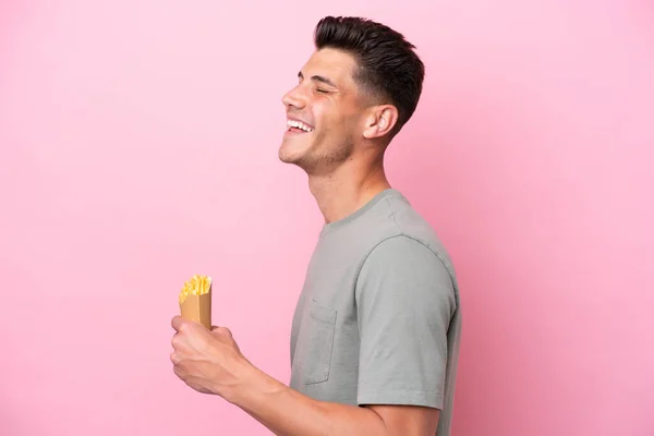 Joven Hombre Caucásico Sosteniendo Chips Fritos Aislados Sobre Fondo Rosa —  Fotos de Stock