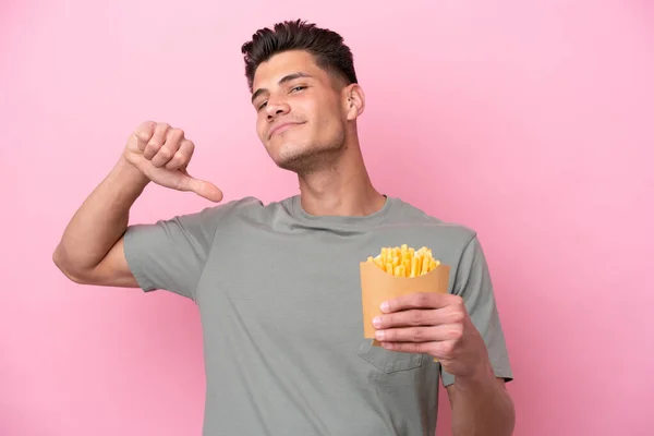 Ung Kaukasier Man Håller Stekt Chips Isolerad Rosa Bakgrund Stolt — Stockfoto