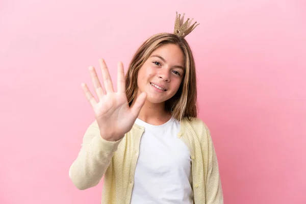 Little princess with crown isolated on pink background counting five with fingers