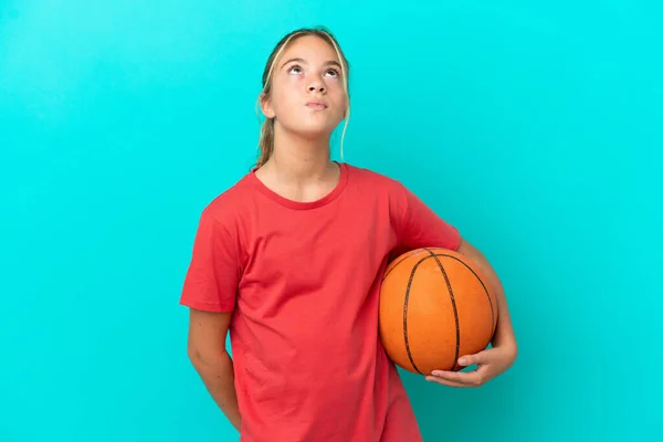 Pequeña Chica Caucásica Jugando Baloncesto Aislado Sobre Fondo Azul Mirando —  Fotos de Stock