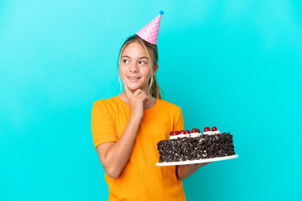 Little Caucasian Girl Holding Birthday Cake Isolated Blue Background Thinking — стоковое фото